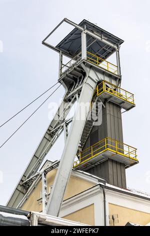 Un arbre de palan de mine contre un ciel gris. Gros plan des roues en haut de l'arbre. Banque D'Images