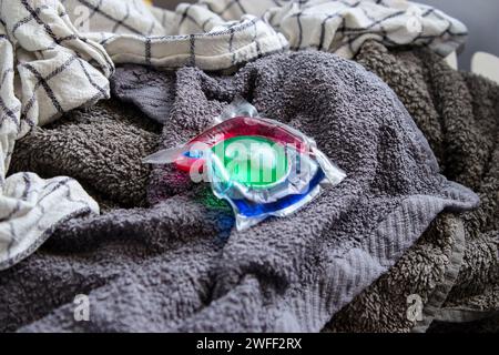 Un gel de lavage écologique coloré en capsule sur le linge dans un panier, laver les vêtements à la maison Banque D'Images