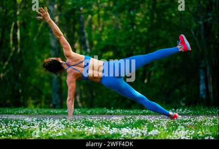 Athlète féminine s'entraînant portant des vêtements de sport parmi les cerisiers Banque D'Images