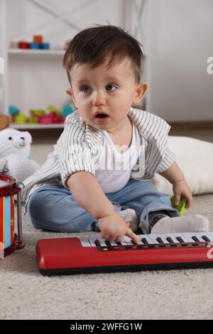 Mignon petit garçon jouant du piano jouet à la maison Banque D'Images