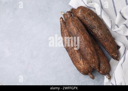 Racines fraîches de manioc sur table grise, vue de dessus. Espace pour le texte Banque D'Images