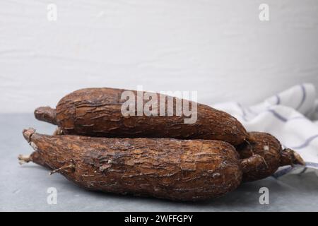 Racines de manioc entières fraîches sur table grise, gros plan Banque D'Images