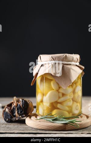 Ail au miel dans un pot en verre et ail noir fermenté sur une table en bois Banque D'Images