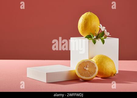 Un citron et des fleurs blanches sont affichés sur un podium en cube blanc sur un fond rose. Podium carré vide pour scène vitrine produit de beauté de Lemon Banque D'Images