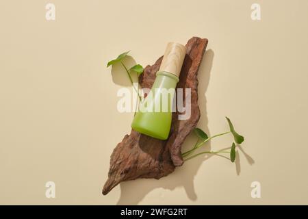 Pot vert sans étiquette mis sur une branche d'arbre sur un fond beige. Produit cosmétique extrait de Gotu kola (Centella asiatica) fournissant des anti-agi Banque D'Images
