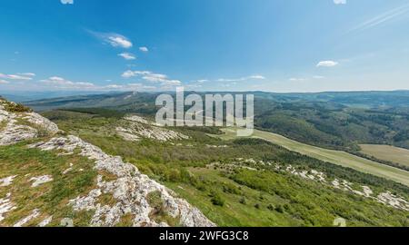 Large vue panoramique sur le paysage de montagne avec des collines verdoyantes sous un ciel bleu clair, beauté naturelle tranquille, parfait pour les amateurs de plein air. Banque D'Images