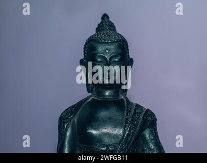 Un gros plan du visage de la statue de Bouddha sur un fond violet Banque D'Images