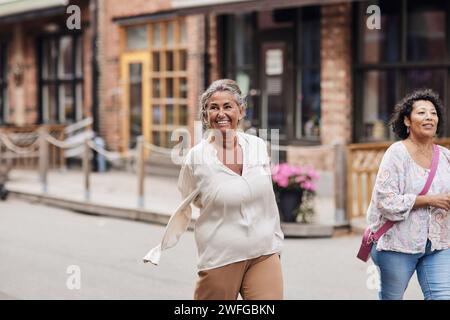 Femme handicapée souriante se promenant avec une amie tout en marchant dans la rue Banque D'Images