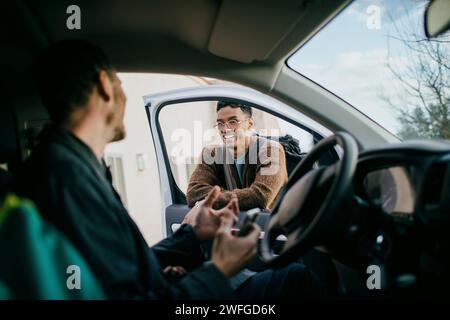 Homme souriant regardant un ami assis à l'intérieur du van Banque D'Images