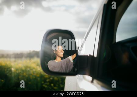 Heureuse jeune femme conduisant une camionnette vue à travers le rétroviseur latéral Banque D'Images