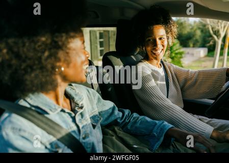 De jeunes femmes heureuses assises en voiture Banque D'Images