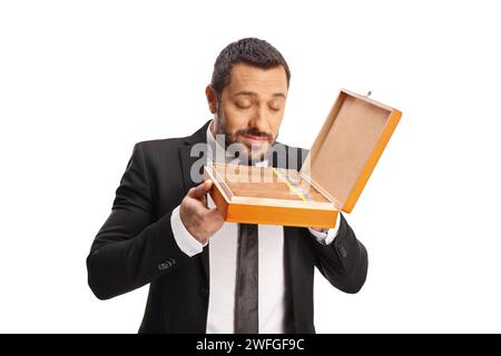 Heureux jeune homme sentant une boîte de cigares et souriant isolé sur fond blanc Banque D'Images