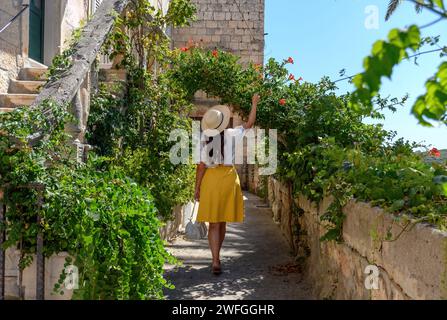 Vue arrière d'une jeune femme marchant dans une ruelle idyllique de la vieille ville méditerranéenne à Korcula, Croatie Banque D'Images