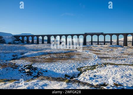 Un train du Nord traverse le célèbre viaduc de Ribblehead un jour d'hiver dans les Yorkshire Dales, avec Ingleborough enneigé en arrière-plan Banque D'Images