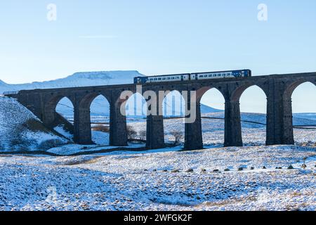 Un train du Nord traverse le célèbre viaduc de Ribblehead un jour d'hiver dans les Yorkshire Dales, avec Ingleborough enneigé en arrière-plan Banque D'Images