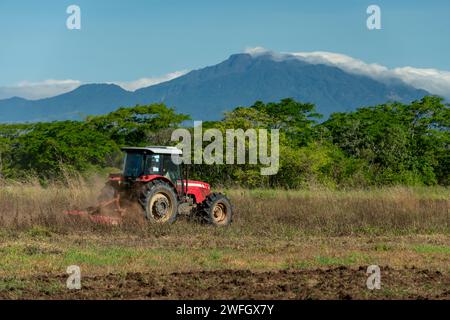 Ciel bleu au-dessus du tracteur labourant un champ avec le volcan Baru en arrière-plan, Chiriqui, Panama, Amérique centrale - photo stock Banque D'Images