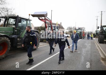 Les agriculteurs du syndicat CR47 (coordination rurale 47) font face à des gendarmes les empêchant d'aller plus loin à Sigloy près d'Orléans, France le 31 janvier 2024, en route pour bloquer le marché de Rungis, en périphérie de Paris. Le président français Macron a exhorté l’Union européenne à faire des concessions aux agriculteurs furieux qui ont juré d’encercler la capitale et de « affamer les Parisiens » en coupant les approvisionnements alimentaires. Huit routes clés à l'entrée et à la sortie de Paris sont actuellement bloquées par plus d'un millier de tracteurs, tandis que des balles de foin le long des routes ont été incendiées et des épouvantails suspendus aux ponts. Des dizaines d'autres Banque D'Images