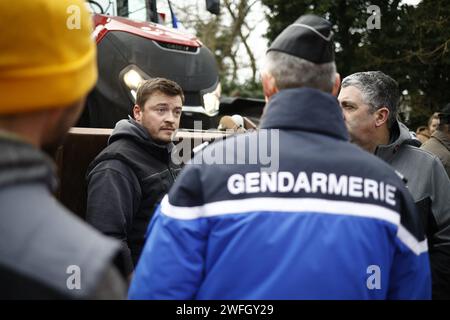 Les agriculteurs du syndicat CR47 (coordination rurale 47) font face à des gendarmes les empêchant d'aller plus loin à Sigloy près d'Orléans, France le 31 janvier 2024, en route pour bloquer le marché de Rungis, en périphérie de Paris. Le président français Macron a exhorté l’Union européenne à faire des concessions aux agriculteurs furieux qui ont juré d’encercler la capitale et de « affamer les Parisiens » en coupant les approvisionnements alimentaires. Huit routes clés à l'entrée et à la sortie de Paris sont actuellement bloquées par plus d'un millier de tracteurs, tandis que des balles de foin le long des routes ont été incendiées et des épouvantails suspendus aux ponts. Des dizaines d'autres Banque D'Images