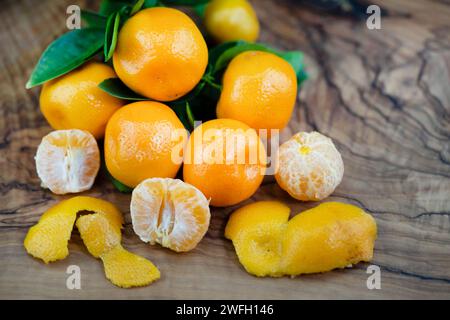 Calamondin, Calomondin, Camalmansi (Citrus madurensis, Citrofortunella microcarpa, Citrus fortunella, citrus mitis), fruits sur la table, partiellement pelés Banque D'Images