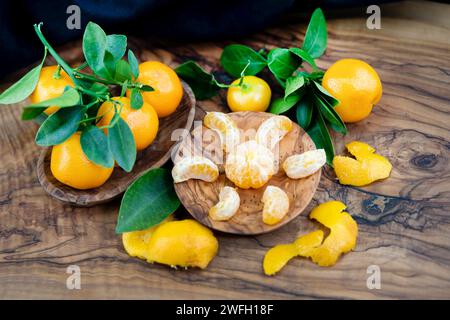 Calamondin, Calomondin, Camalmansi (Citrus madurensis, Citrofortunella microcarpa, Citrus fortunella, citrus mitis), fruits sur la table, partiellement pelés Banque D'Images