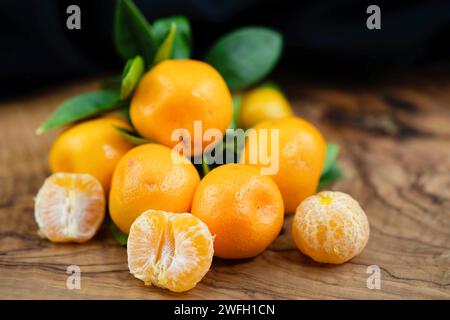 Calamondin, Calomondin, Camalmansi (Citrus madurensis, Citrofortunella microcarpa, Citrus fortunella, citrus mitis), fruits sur la table, partiellement pelés Banque D'Images