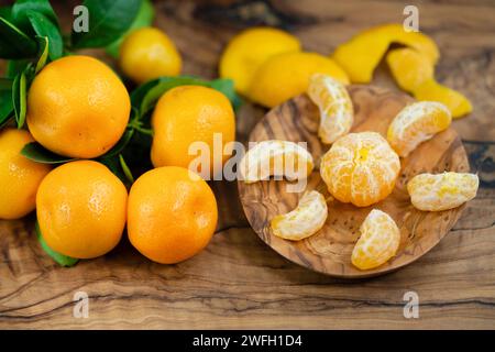 Calamondin, Calomondin, Camalmansi (Citrus madurensis, Citrofortunella microcarpa, Citrus fortunella, citrus mitis), fruits sur la table, partiellement pelés Banque D'Images