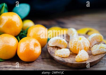 Calamondin, Calomondin, Camalmansi (Citrus madurensis, Citrofortunella microcarpa, Citrus fortunella, citrus mitis), fruits sur la table, partiellement pelés Banque D'Images