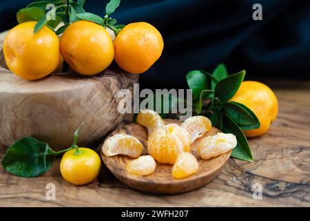 Calamondin, Calomondin, Camalmansi (Citrus madurensis, Citrofortunella microcarpa, Citrus fortunella, citrus mitis), fruits sur la table, partiellement pelés Banque D'Images