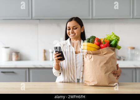 Joyeuse jeune femme indienne commander l'épicerie en ligne Banque D'Images