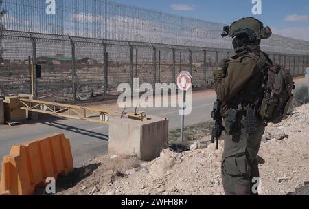 Un soldat israélien monte la garde au terminal de Nitzana où des camions entrent en Israël depuis l’Égypte pour inspection avant d’être envoyés à Rafah pour entrer dans Gaza le 30 janvier 2024 à Nitzana, en Israël. Banque D'Images