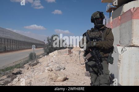 Un soldat israélien monte la garde au terminal de Nitzana où des camions entrent en Israël depuis l’Égypte pour inspection avant d’être envoyés à Rafah pour entrer dans Gaza le 30 janvier 2024 à Nitzana, en Israël. Banque D'Images