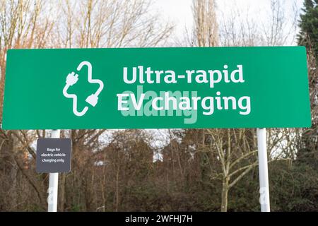 Gros plan d'un panneau vert et blanc montrant un point de recharge ultra-rapide de véhicule électrique dans un parking de supermarché de Sainsbury, au Royaume-Uni. Banque D'Images
