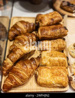 Croissants dorés et pâtisseries assorties présentés sur un plateau en bois dans un coffret de boulangerie. Banque D'Images