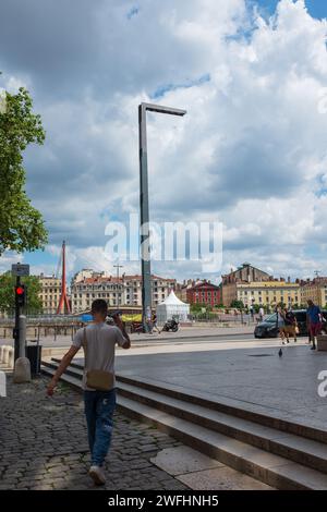 Lyon, France, 2023. Un jeune homme marche vers le Quai Romain Rolland et la passerelle du Palais de Justice (verticale) Banque D'Images