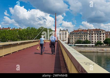 Lyon, France, 2023. Un couple de personnes âgées énergique traversant le pont du Palais de Justice, avec la Presqu'île (2e arrondissement) en arrière-plan Banque D'Images
