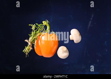 Champignons champignons et paprika avec branche de thym sur fond bleu foncé. Banque D'Images