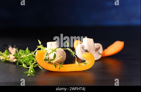 Champignons champignons et paprika avec branche de thym sur fond sombre. Banque D'Images