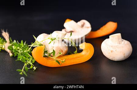 Champignons champignons et paprika avec branche de thym sur fond sombre. Banque D'Images