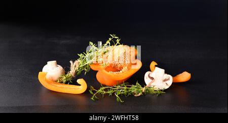 Champignons champignons et paprika avec branche de thym sur fond sombre. Banque D'Images