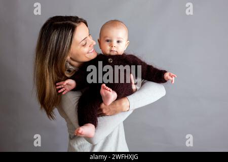 Jeune mère, caressant son nouveau-né garçon, le tenant dans ses bras, différentes positions de tenir bébé, souriant du bonheur Banque D'Images