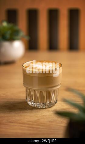 Vue latérale du café au latte chaud avec latte art dans une tasse en verre Banque D'Images