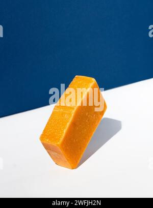 Pain de savon orange sur un fond blanc-bleu. Concept créatif de cosmétiques faits à la main à partir de produits naturels. Banque D'Images