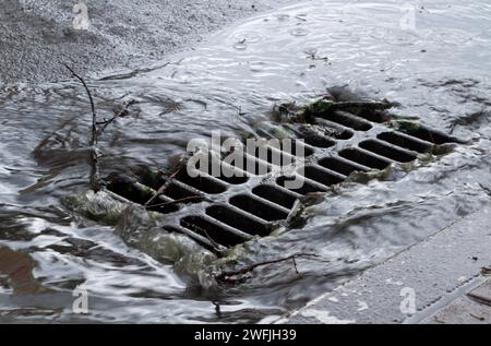 L'eau de pluie s'écoule dans un égout pluvial. Système d'égout urbain pour drainer l'eau pendant les fortes pluies Banque D'Images