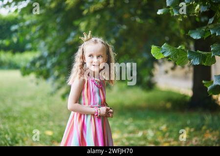 Mignonne fille d'enfant d'âge préscolaire dans la couronne de princesse dans le parc ou la forêt sur un jour d'été. Activités de plein air pour les enfants Banque D'Images
