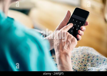 Vieille femme senior et code de numéro de mot de passe de téléphone contre l'escroquerie en ligne. Cybersécurité. La personne âgée mature protège les données bancaires avec un verrou à broche. Banque D'Images