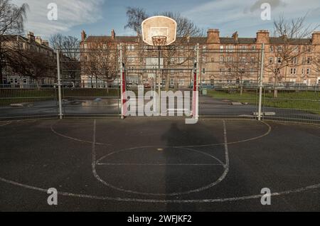 Édimbourg, Écosse, 19 janvier 2024 - panneau de basket-ball avec l'anneau métallique cerceau sur les terrains de basket-ball extérieurs dans le parc avec de vieux bâtiments backgrou Banque D'Images