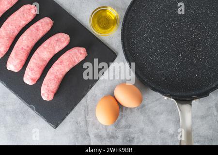 Bratwurst crue fraîche (saucisses de porc), œufs, huile d'olive gros plan sur une table de cuisine, ponte plate Banque D'Images