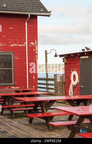 Des tables de pique-nique rouges vacantes sont alignées à l'extérieur du quai public historique de Coupeville, Whidbey Island, dans l'État de Washington. Banque D'Images