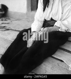 Comté de Vrancea, République socialiste de Roumanie, env. 1979. Mains d'une femme âgée portant des vêtements traditionnels faits à la main. Banque D'Images