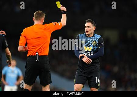 Connor Roberts de Burnley (à droite) reçoit un carton jaune de l'arbitre Sam Barrott lors du match de Premier League à l'Etihad Stadium, Manchester. Date de la photo : mercredi 31 janvier 2024. Banque D'Images